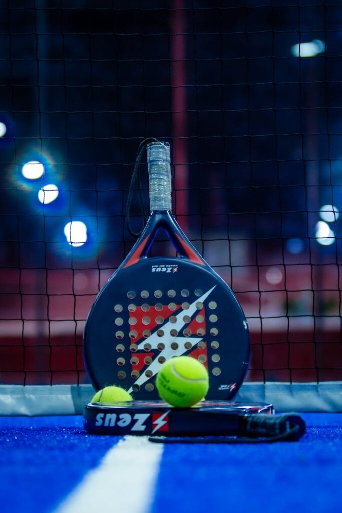 A padel racket and yellow balls placed on a vibrant blue padel court, perfect for sports enthusiasts.